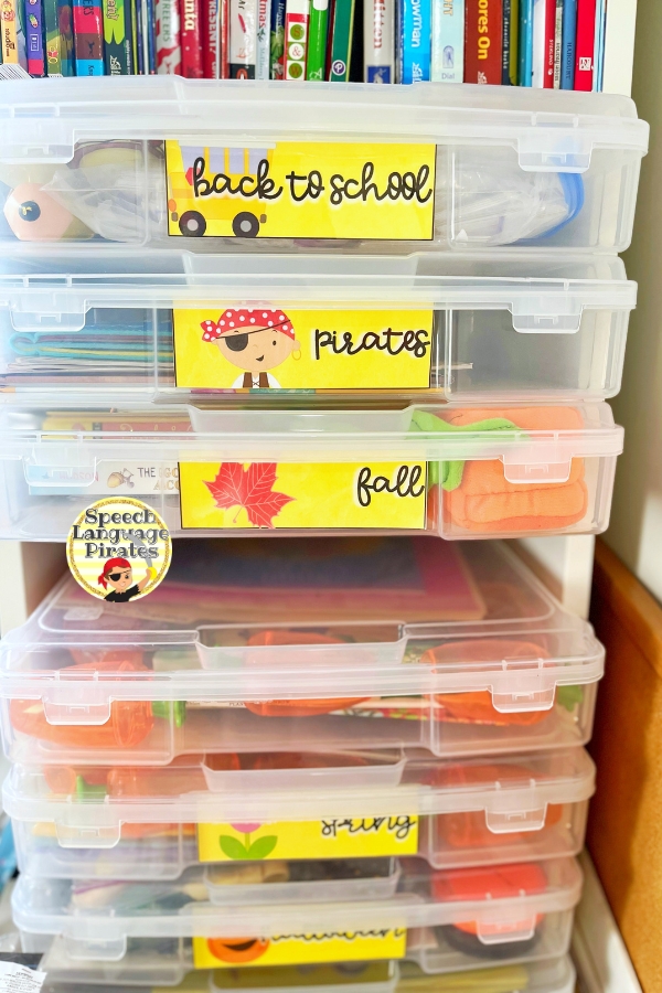 scrapbook boxes with themed speech therapy materials stacked on ikea bookshelf
